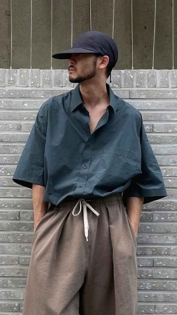Jet-black curved visor cap + Forest-teal boxy half-sleeve shirt + Taupe drawstring wide trousers + Low-profile black sneakers