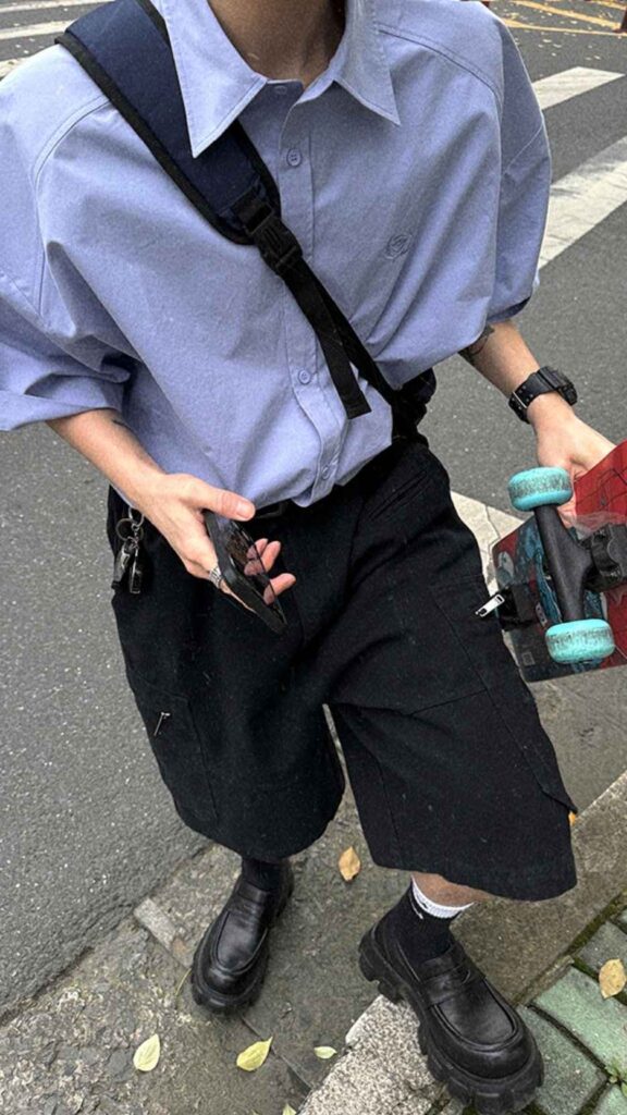 Navy utility cross-body harness + Powder-blue oversized shirt + Black cargo knee shorts + High-rib white socks + Lug-soled black loafers