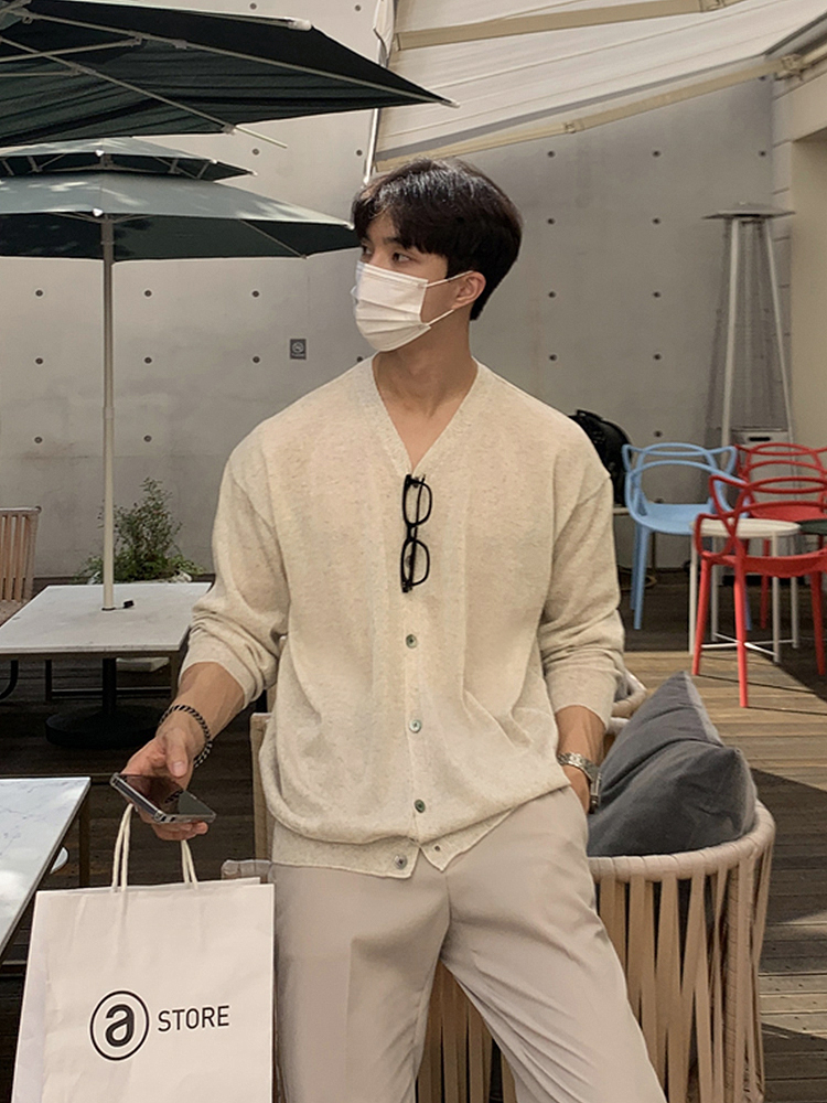 Crew-cut hair + white face mask + tortoiseshell glasses lanyard + oat-milk V-neck cardigan + light-taupe pleated trousers