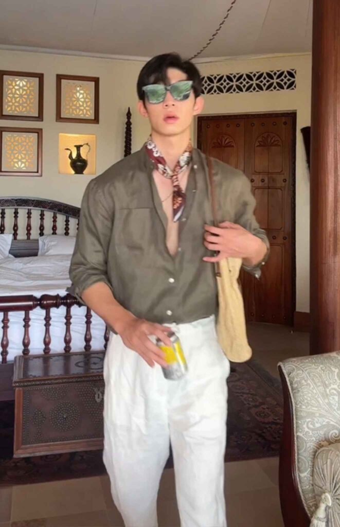 Reflective leaf shades + Paisley silk neck scarf + Olive linen shirt (deep-placket, half-tucked) + White crushed-linen trousers + Raffia shoulder tote