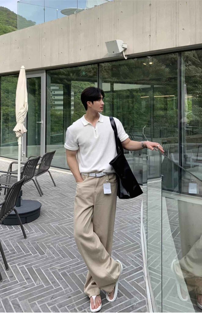 Ivory knit polo with half-zip + Slim steel watch + White perforated belt + Sandstone wide chinos + Patent black vinyl tote + White flip-flops
