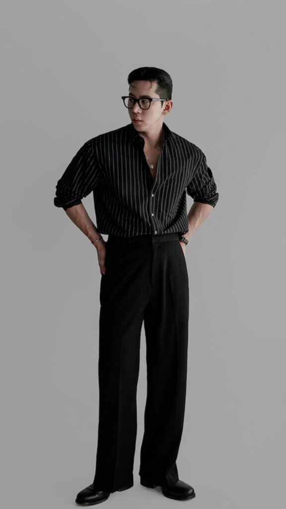 Slicked-back hair + Black wayfarer glasses + Charcoal pinstripe spread-collar shirt + High-waist black drape trousers + Glossy black derby shoes