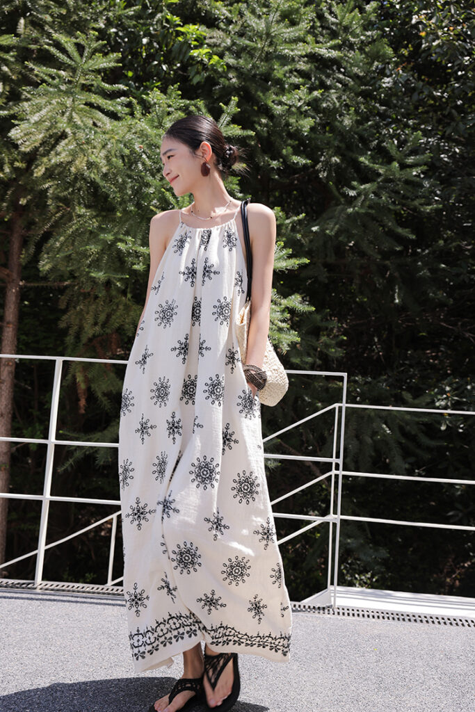 Sleek bun + resin hoop earrings + monochrome mandala halter maxi dress + black flip-flops