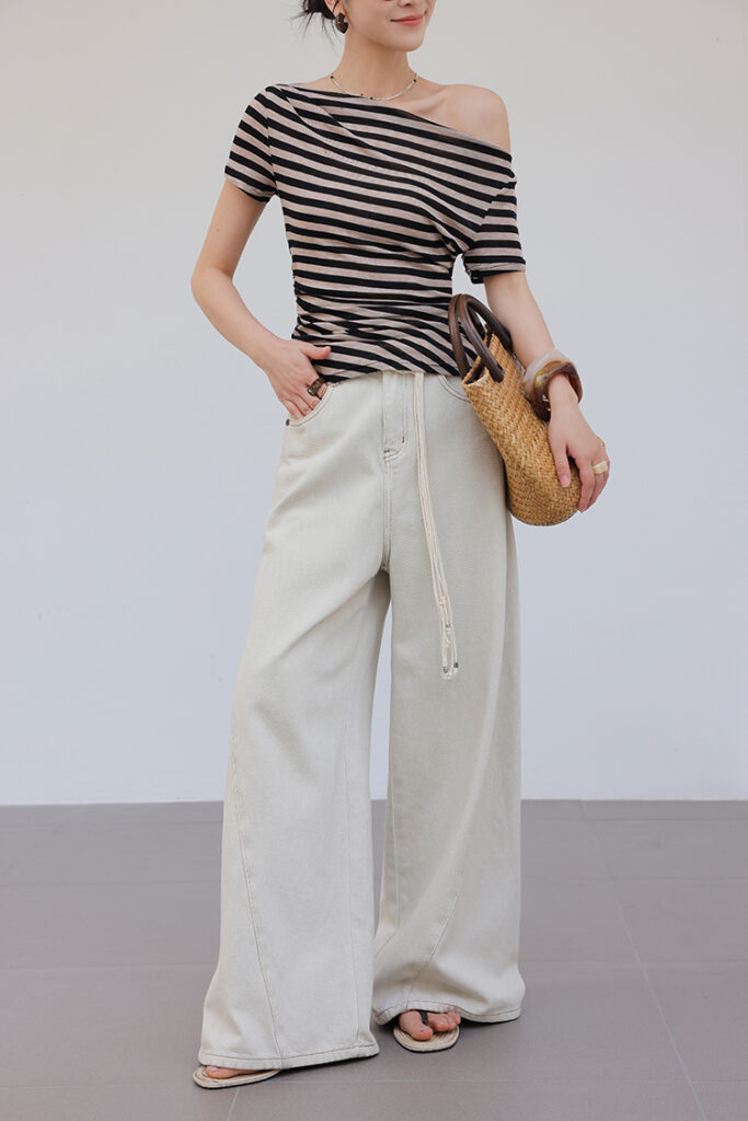 Messy top-knot + black-and-taupe striped off-shoulder tee + cream wide-leg jeans + taupe slides