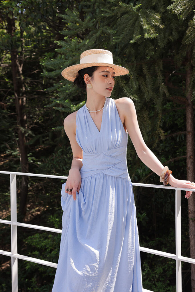 Straw boater hat + sky-blue halter wrap maxi dress + tortoiseshell bangles
