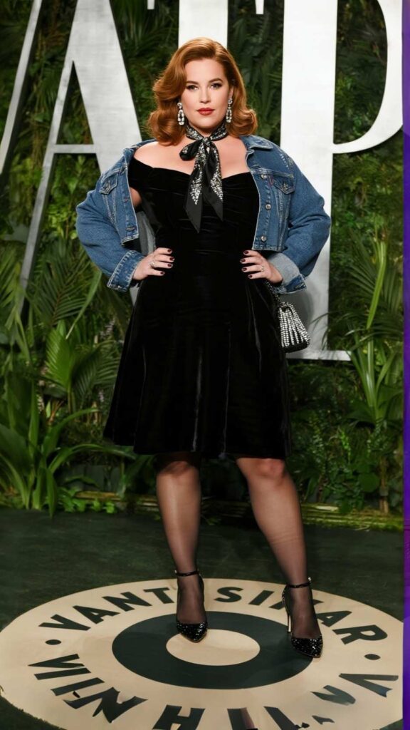 Side-part Hollywood waves + Crystal drops + Satin scarf + Cropped denim jacket + Off-shoulder fit-and-flare dress + Beaded wristlet + Sheer thigh-highs + Cone heels